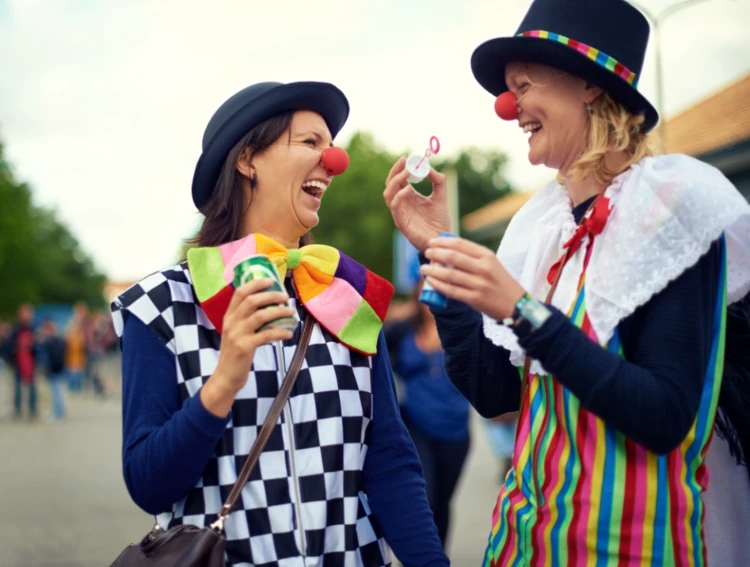Zwei Frauen in Clownskostümen lachen auf Straßenfest