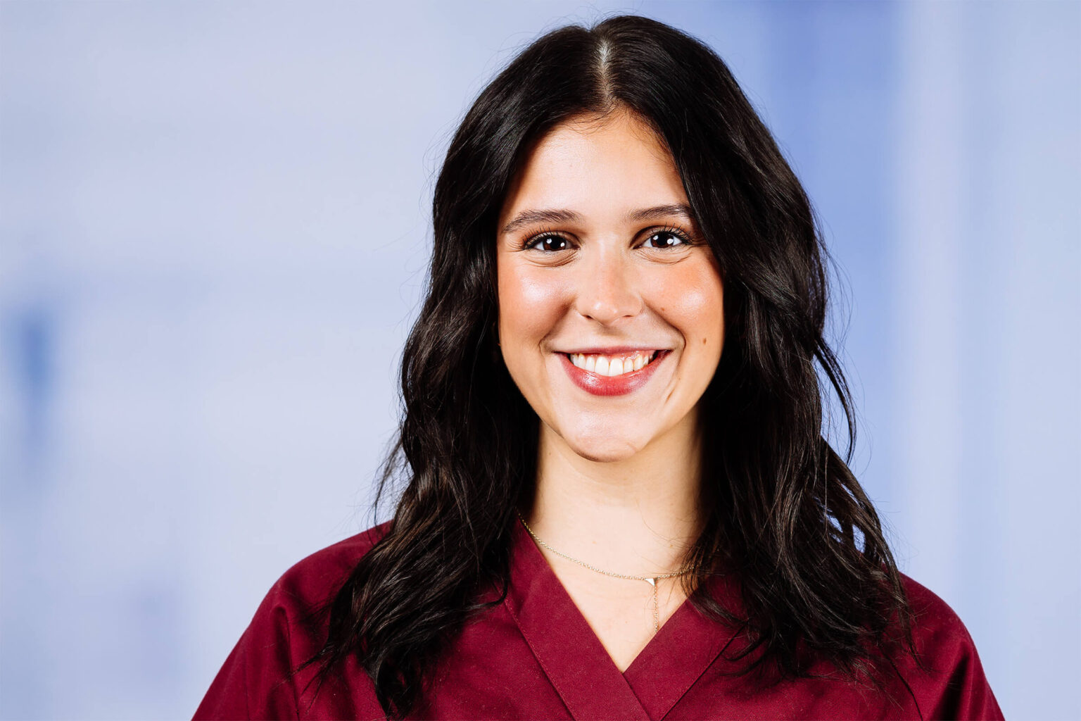 Lächelnde Frau mit dunklen Haaren in bordeauxroter Kleidung