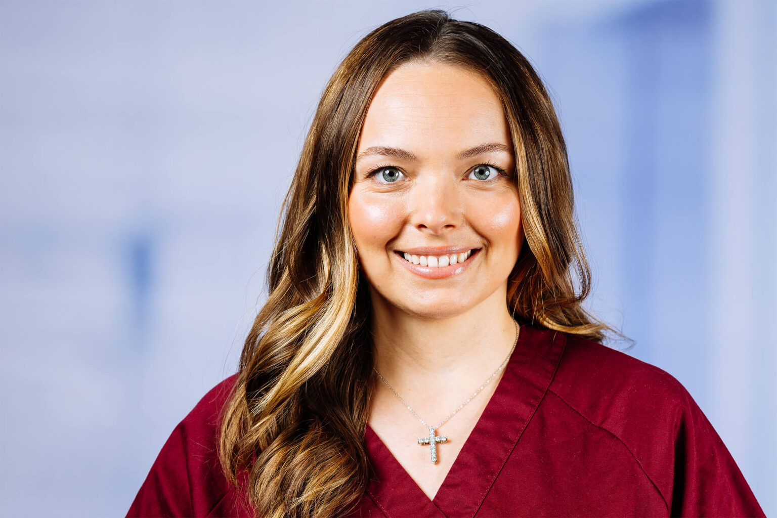 Lächelnde Frau mit lockigen Haaren und Kreuzanhänger