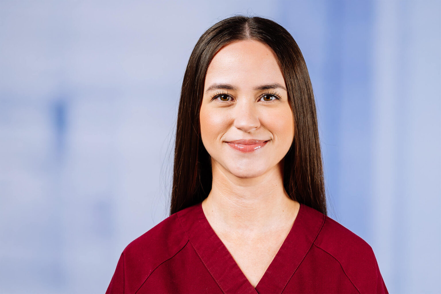 Lächelnde Frau in rotem Oberteil vor blauem Hintergrund