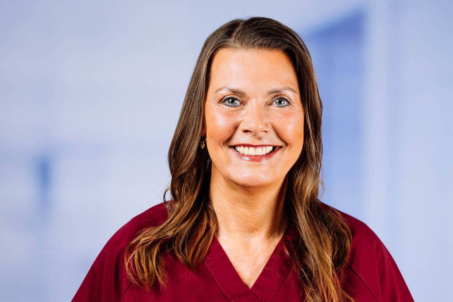 Lächelnde Frau mit braunen Haaren im roten Oberteil